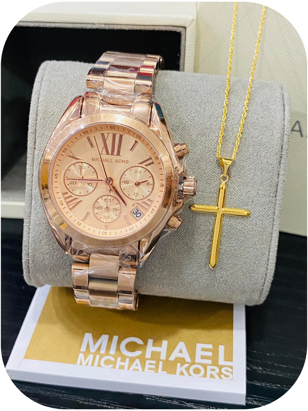 Michael Kors wristwatch paired with a gold cross pendant necklace